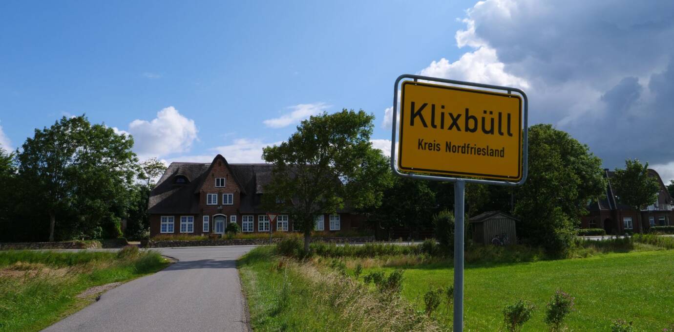 Ortsschild Klixbüll vor Gebäude