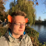 Mann mit Herbstblättern am Flussufer
