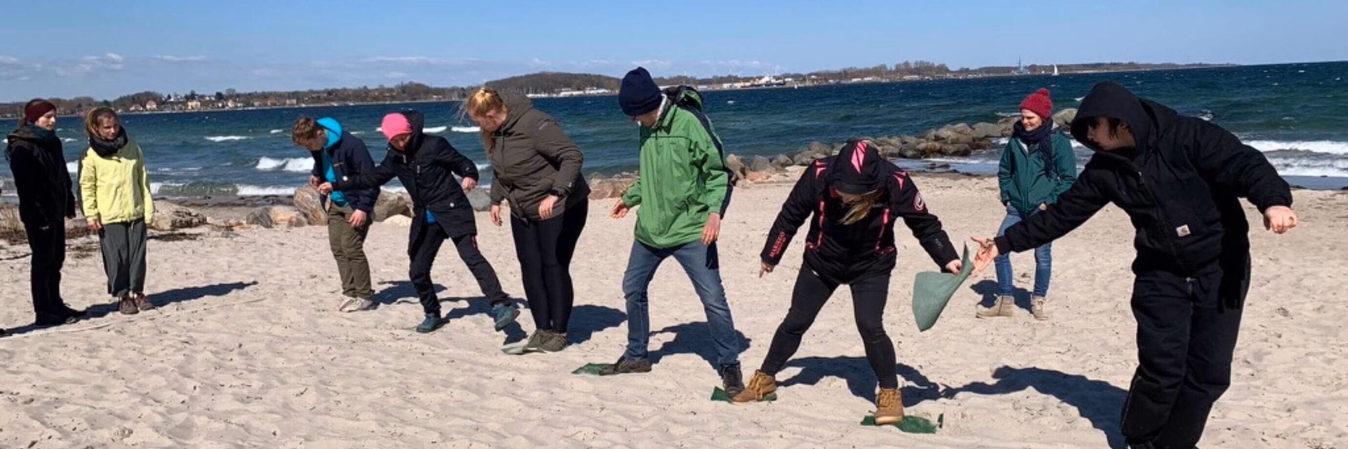 Gruppe von Menschen spielt am Strand im Sand.