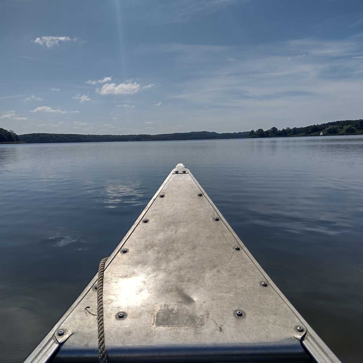 Bootsfahrt auf ruhigem See bei klarem Himmel.