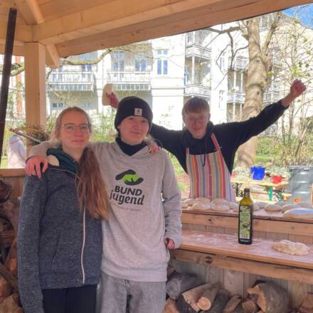Drei junge Menschen beim Backen im Freien.