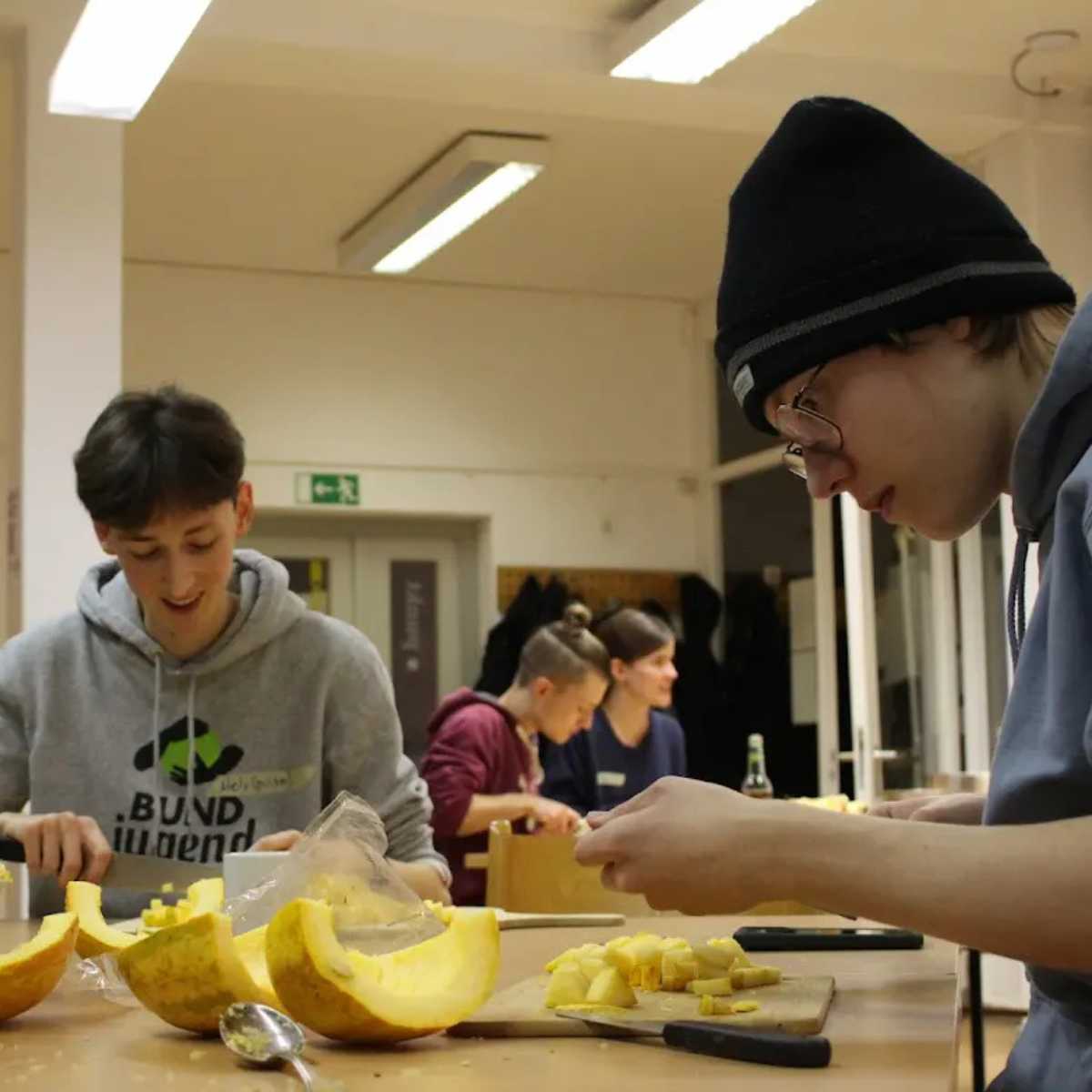 Junge Leute schneiden Kürbis in der Küche.