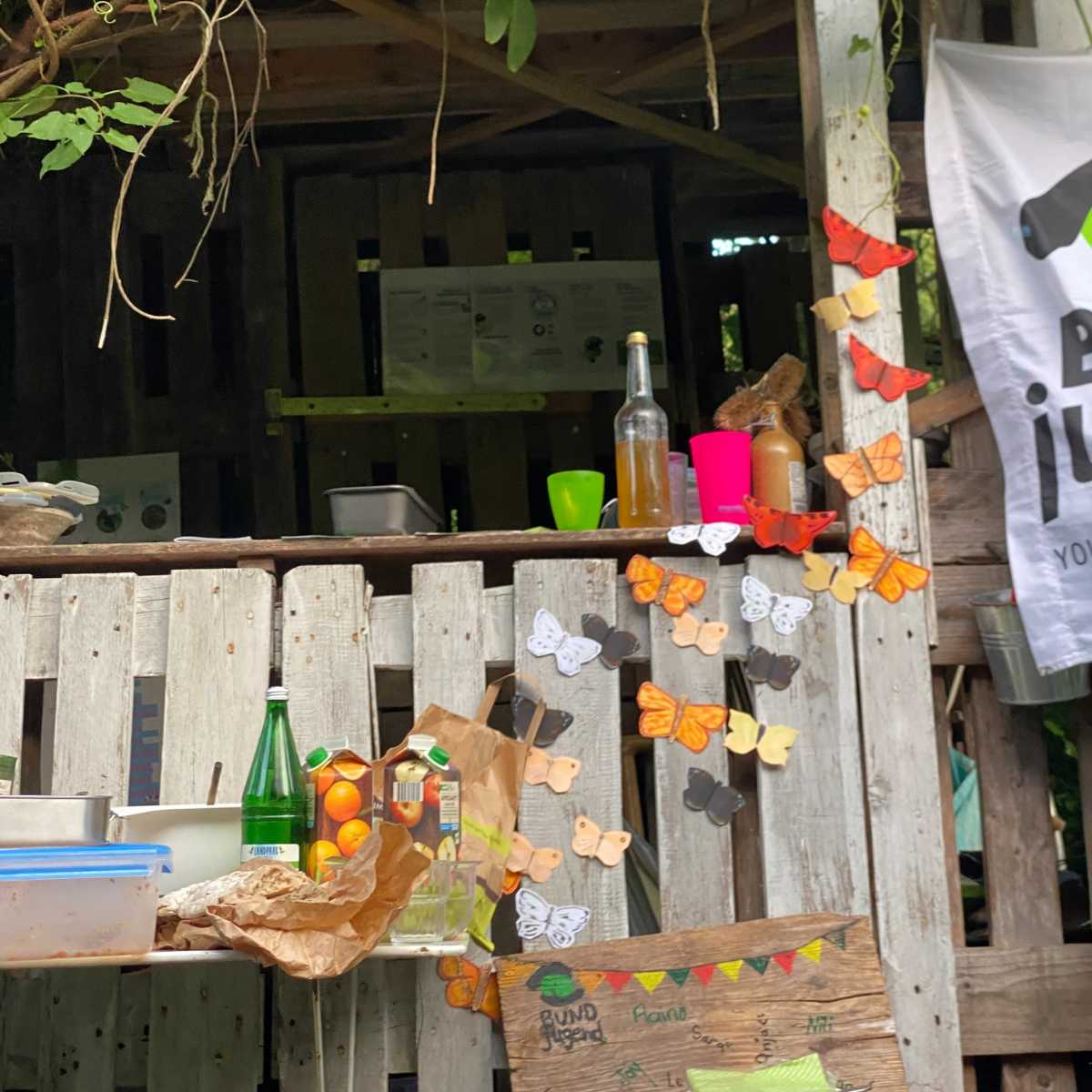 Holzstand dekoriert mit bunten Schmetterlingen und Getränken.