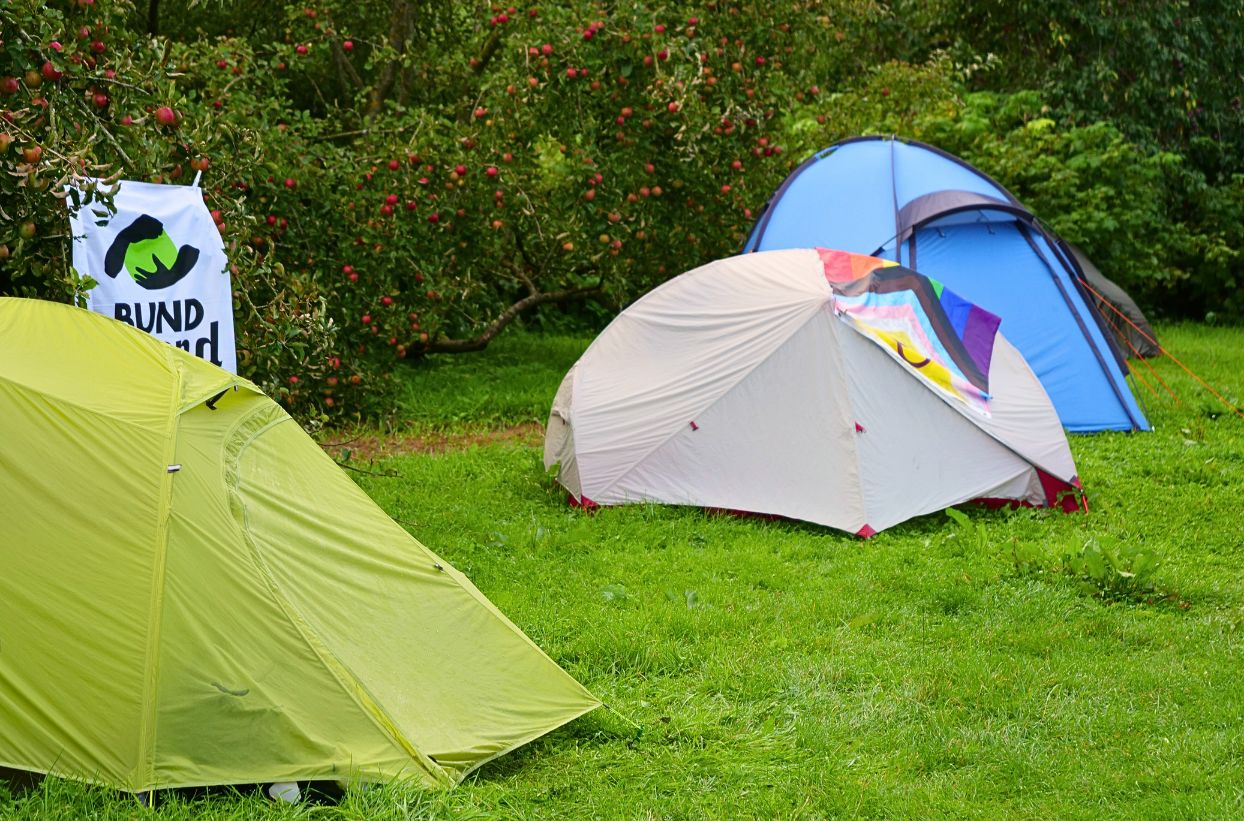 Bunte Zelte im Grünen mit Apfelbäumen.